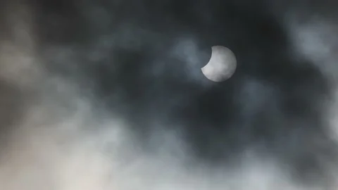 Partial solar eclipse with dark clouds passing in the foreground Stock Footage 221096226