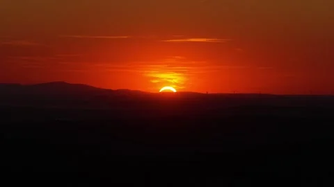 Partial solar eclipse during a dramatic red sunset over mountain Vidéo 348078673