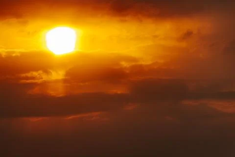 A partial solar eclipse glows through dramatic red-orange clouds Stock Photos