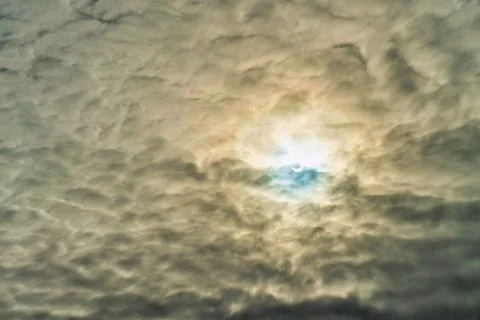Partial solar eclipse passing behind the clouds. Stock Photos