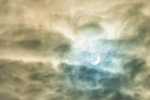 Partial solar eclipse passing behind the clouds. Stock Photos
