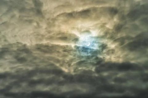 Partial solar eclipse passing behind the clouds. Stock Photos
