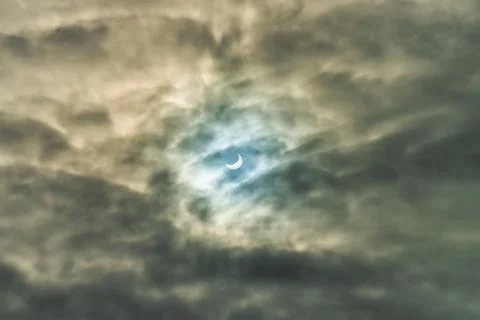 Partial solar eclipse passing behind the clouds. Stock Photos