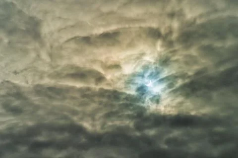 Partial solar eclipse passing behind the clouds. Stock Photos