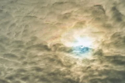 Partial solar eclipse passing behind the clouds. Stock Photos