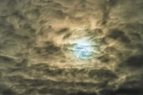 Partial solar eclipse passing behind the clouds. Stock Photos
