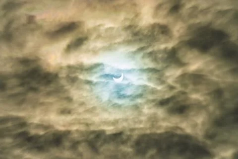 Partial solar eclipse passing behind the clouds. Stock Photos
