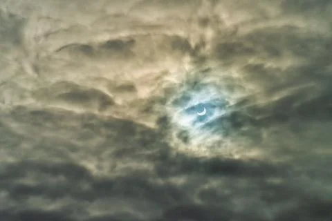 Partial solar eclipse passing behind the clouds. Stock Photos