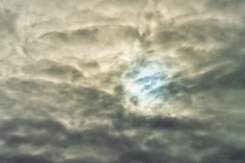 Partial solar eclipse passing behind the clouds. Stock Photos