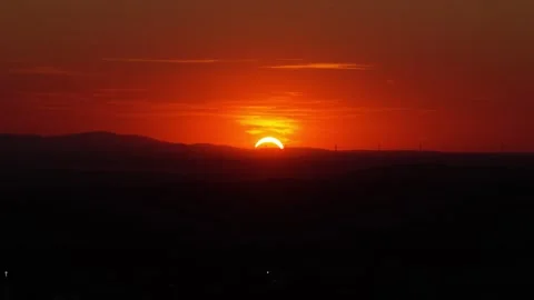 Partial solar eclipse with red sky and mountain silhouette at sunset Stock Footage 348363289