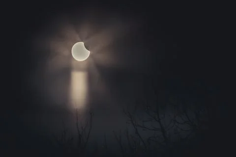 A partial solar eclipse in the sky over Latvia with rays piercing through clouds Stock Photos
