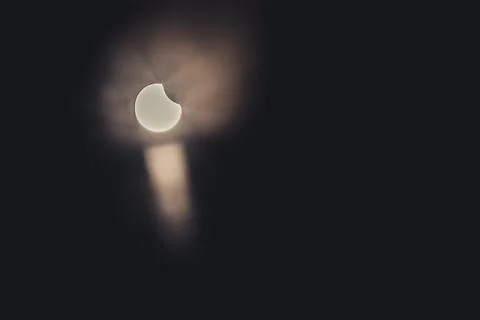 A partial solar eclipse in the sky over Latvia with rays piercing through clouds Stock Photos