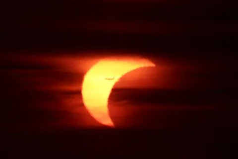 Partial solar eclipse at sunset with an airplane silhouette transit Stock Photos