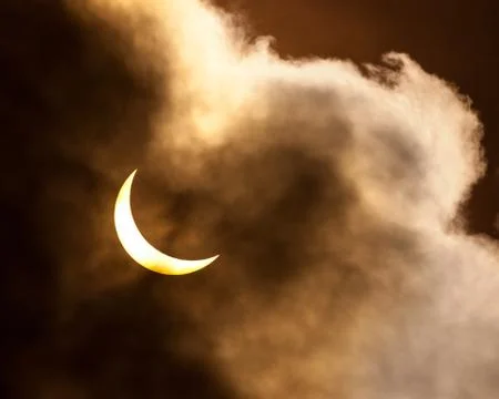 Partial solar eclipse through clouds Stock Photos