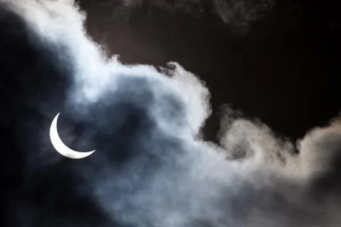 Partial solar eclipse through clouds Stock Photos
