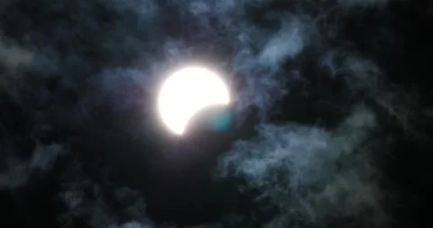 Partial solar eclipse viewed through clouds in a nighttime sky Stock Footage 281706412