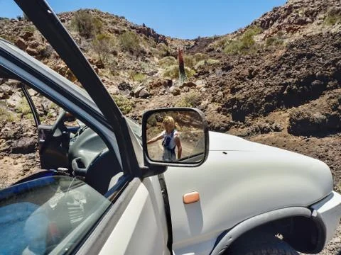 Partial view of a big car, in the right side mirror is a woman to see Stock Photos