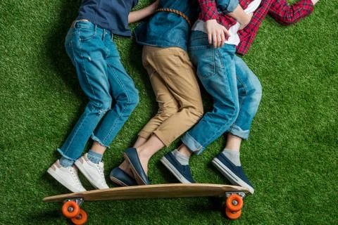 Partial view of children pretending standing on skateboard on green grass Stock Photos