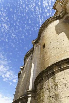 Partial view of the facade of an old stone church with the cloudy blue sky in Stock Photos