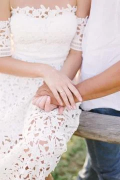 Partial view of lovers holding hands with wild flowers on background. Stock Photos