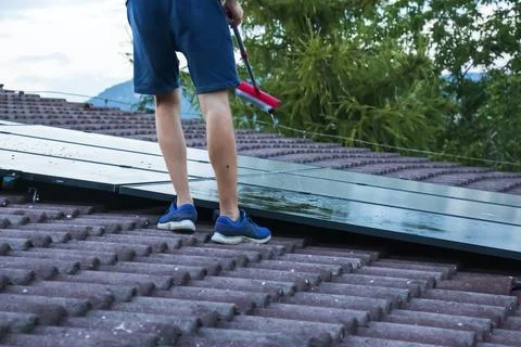 Partial View of Man Cleaning Wet Rooftop Solar Panels Photos