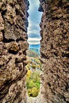 Partial view of a mountain and cloudy skies as seen between stone wall Stock Photos