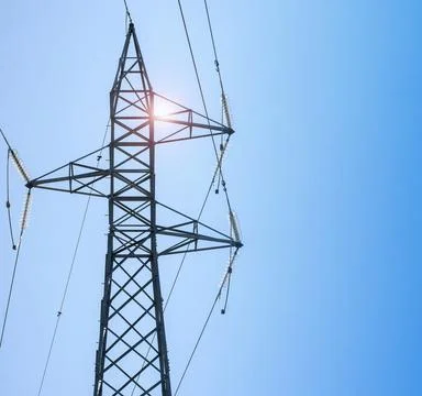 Partial view of a power line tower under a blue sky with a nice reflection Stock Photos