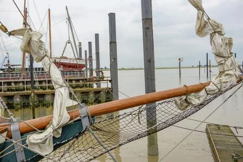 Partial view of a sailing ship at a quiet jetty under a cloudy sky, ditzum, east Stock Photos