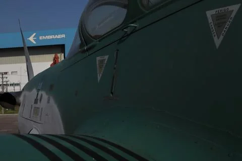 Partial view of a Supertucano plane in the foreground with the Embraer factory Foto stock