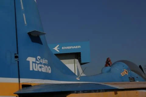 Partial view of a Supertucano plane in the foreground with the Embraer factory Stock Photos