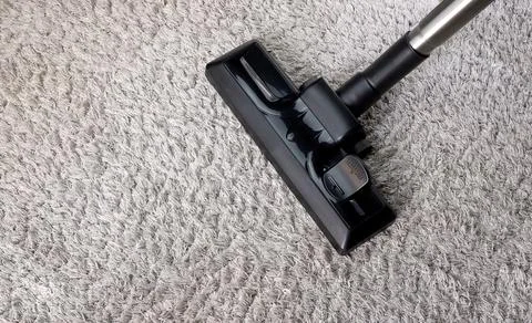 Partial view of a vacuum cleaner on a gray carpet Stock Photos