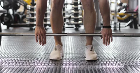 Partial view of weightlifter in white sneakers raising barbell in a gym. Front Vídeo Stock 158726868