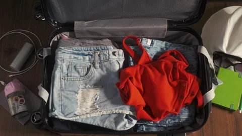 Partial view of woman packing suitcase with summer clothes on floor at home Vídeos de archivo 336235974