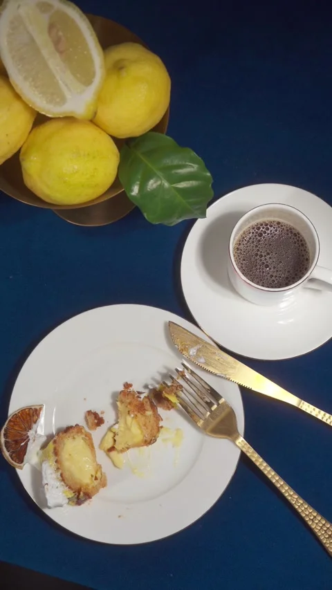 Partially eaten lemon eclair dessert with coffee cup and lemons top view. Stock Footage 335422330
