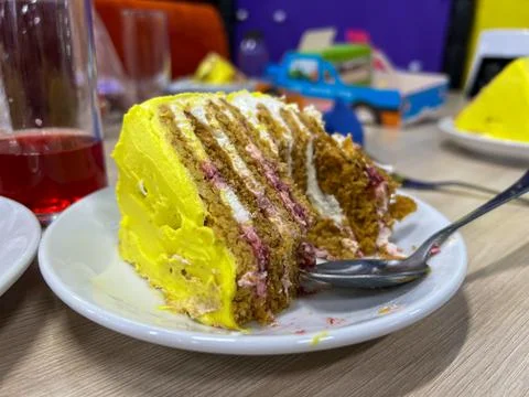 Partially eaten slice of layer cake with yellow frosting and filling on whi.. Stock Photos