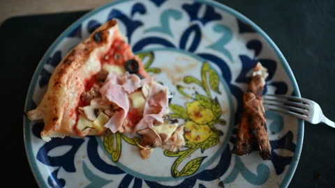 Partially eaten slice of pizza with ham, mushrooms, olives, and cheese on Stock Footage 332628430