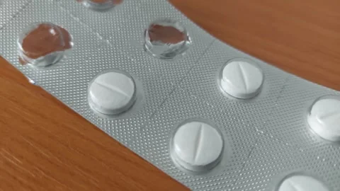 Partially empty blister pack of white pharmaceutical pills on wooden surface Stock Footage 333641420