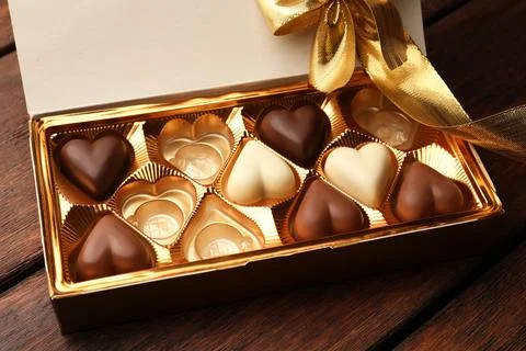 Partially empty box of chocolate candies on wooden table Stock Photos