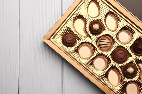Partially empty box of chocolate candies on white wooden table, top view. S.. 스톡 사진