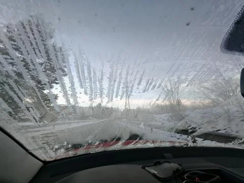 Partially frozen car windshield viewed from the vehicle interior, angled view Stock Photos