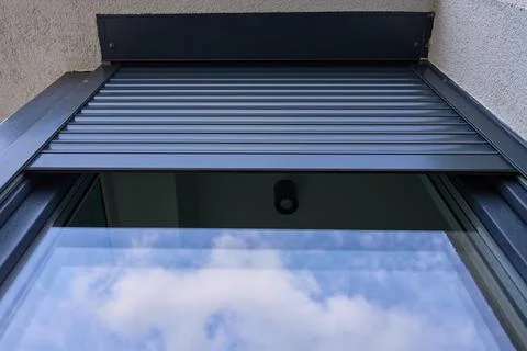 Partially lowered metal roller shutter covers the upper section of an exterio Stock Photos
