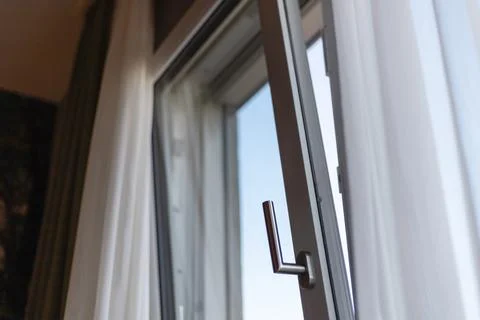 A partially open window allows a glimpse of the clear blue sky, with soft c.. Stock Photos
