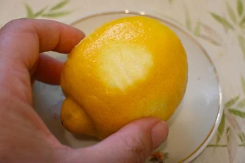 Partially peeled lemon in hand Photos