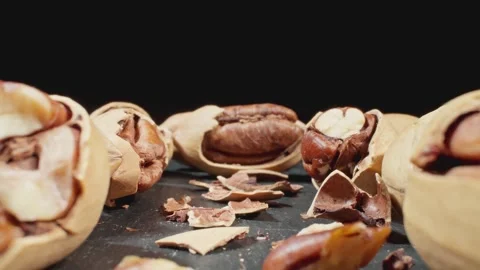 Partially peeled pecans at black background. Tasty nuts on table. Unpeeled pecan Stock Footage 286060553