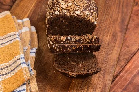 Partially sliced grain brown bread on cutting board, top view Stock Photos