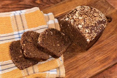 Partially sliced grain brown bread on cutting board, top view Stock Photos