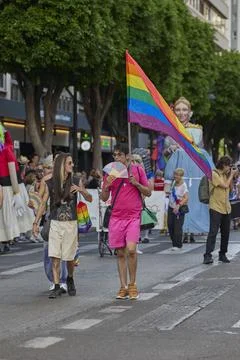 Participant holding rainbow flag while walking in pride parade procession Stock Photos