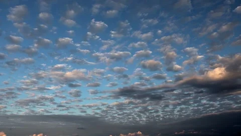 Partly cloudy altocumulus clouds in blue sky during sunset golden hour light Stock Footage 339360188