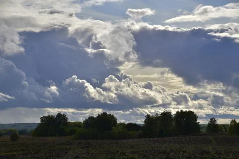Partly cloudy. The bright sun and heavy ragged clouds in the sky. Autumn in t Stock Photos