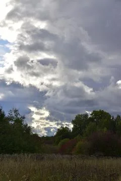 Partly cloudy. The bright sun and heavy ragged clouds in the sky. Autumn in t Stock Photos